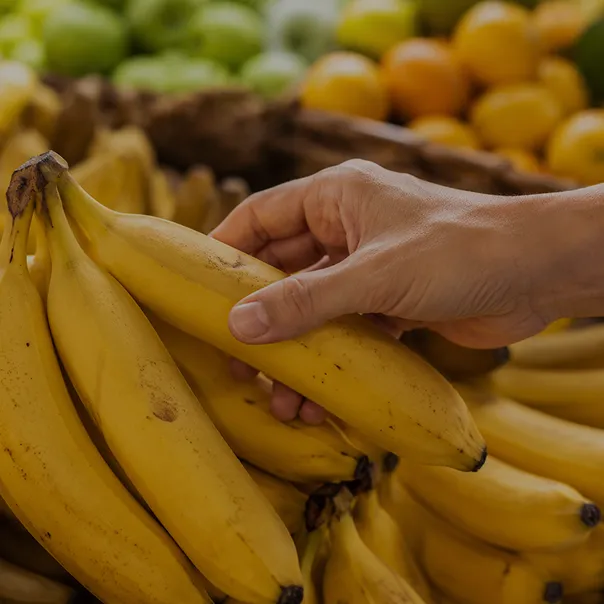 Hand selecting fresh bananas from a market display