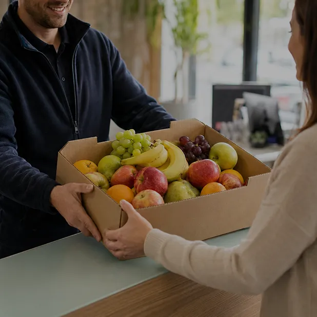Fanfruit team member handing a customer a box of fresh fruit